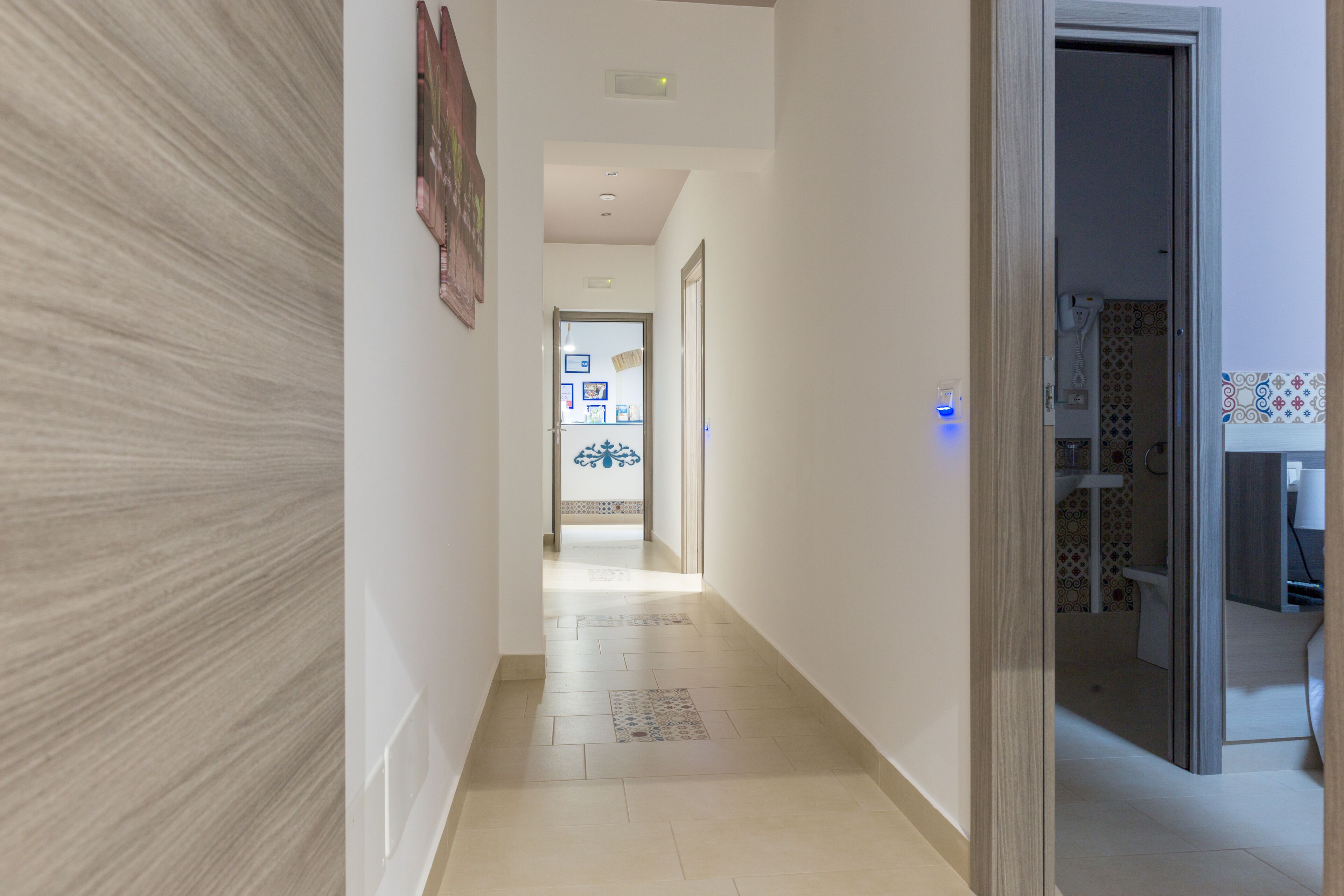 A hallway with a light-colored floor, a door on the right, and a wall with a textured pattern.