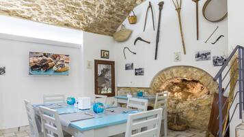 Un comedor con techo de piedra, decoración rústica y un horno de piedra.