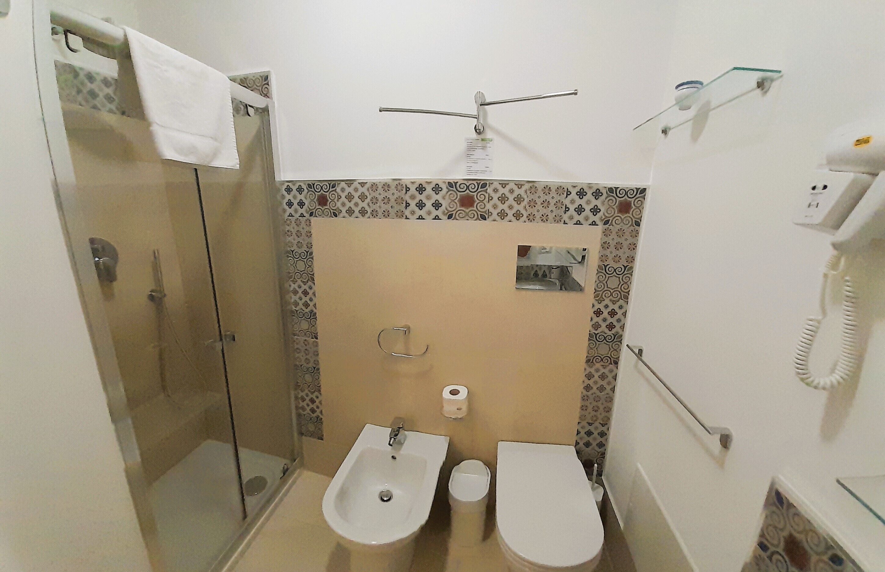 A bathroom with a glass-enclosed shower, a bidet, a toilet, and a towel rack.