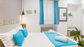 Una habitación de hotel con una cama, un pequeño escritorio, un espejo y una planta en maceta.
