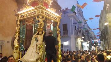 A crowded street with a golden ornate structure, possibly a religious icon, being carried by people.