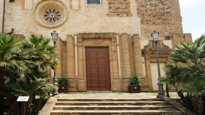 Un edificio histórico con una gran puerta de madera, una ventana circular y fachada de piedra.