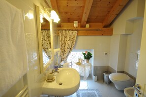 A bathroom with a sink, mirror, toilet, and shower curtain. - Casa Novecento (Feltre)