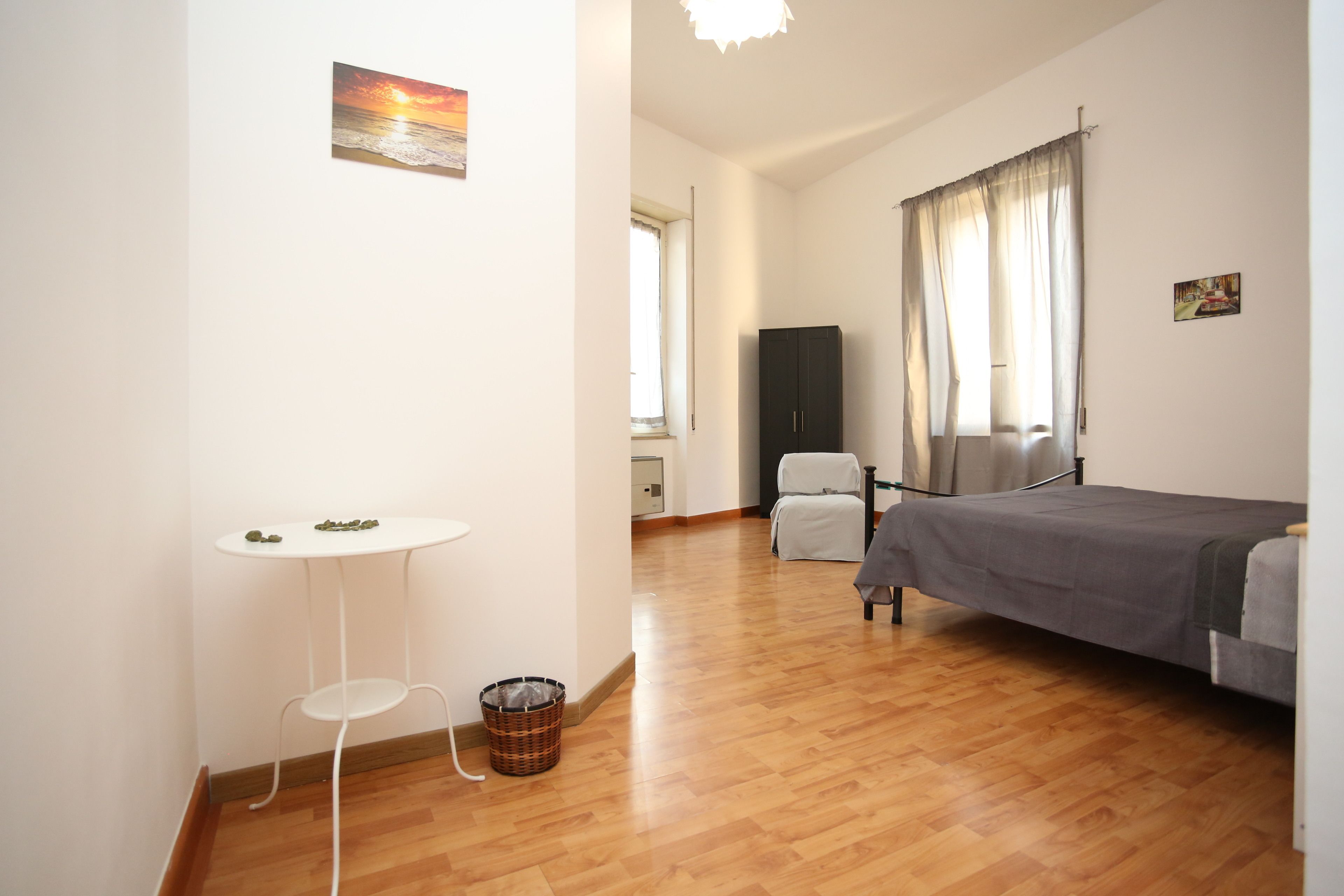 Um quarto com uma cama, uma mesinha, uma cadeira e um guarda-roupa.