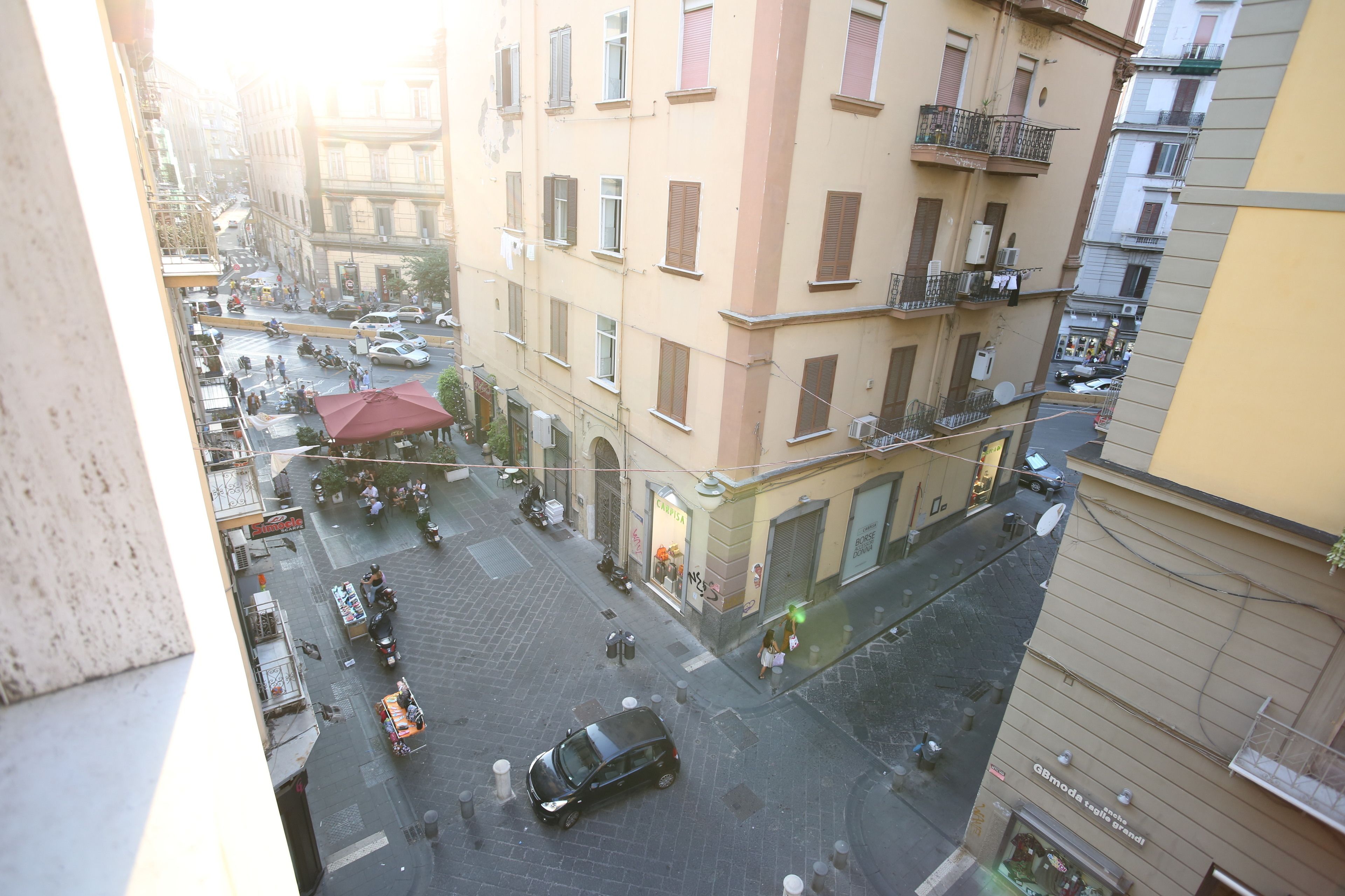 A street view from a high vantage point, capturing a busy urban street with buildings, vehicles, and pedestrians.
