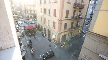 Une vue de rue prise depuis un point d’observation élevé, qui montre une rue animée en milieu urbain, avec des bâtiments, des véhicules et des piétons.