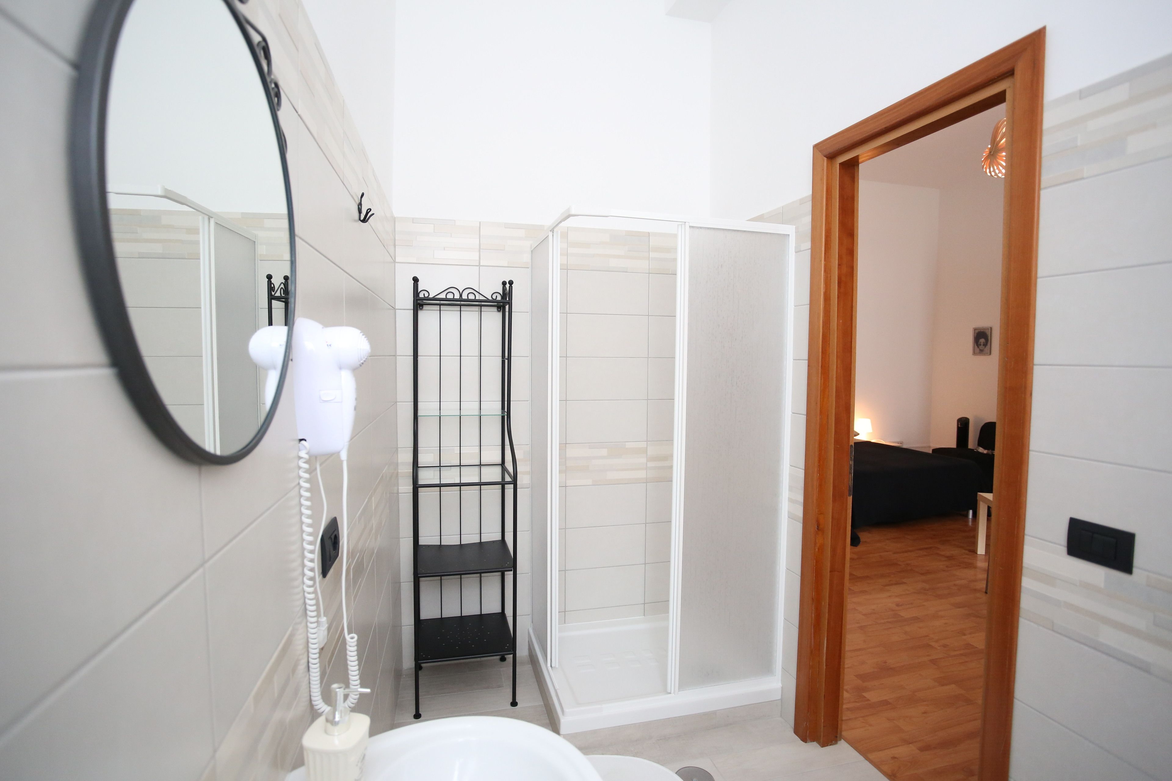 A bathroom with a toilet, a mirror, a hairdryer, and a shower enclosure.