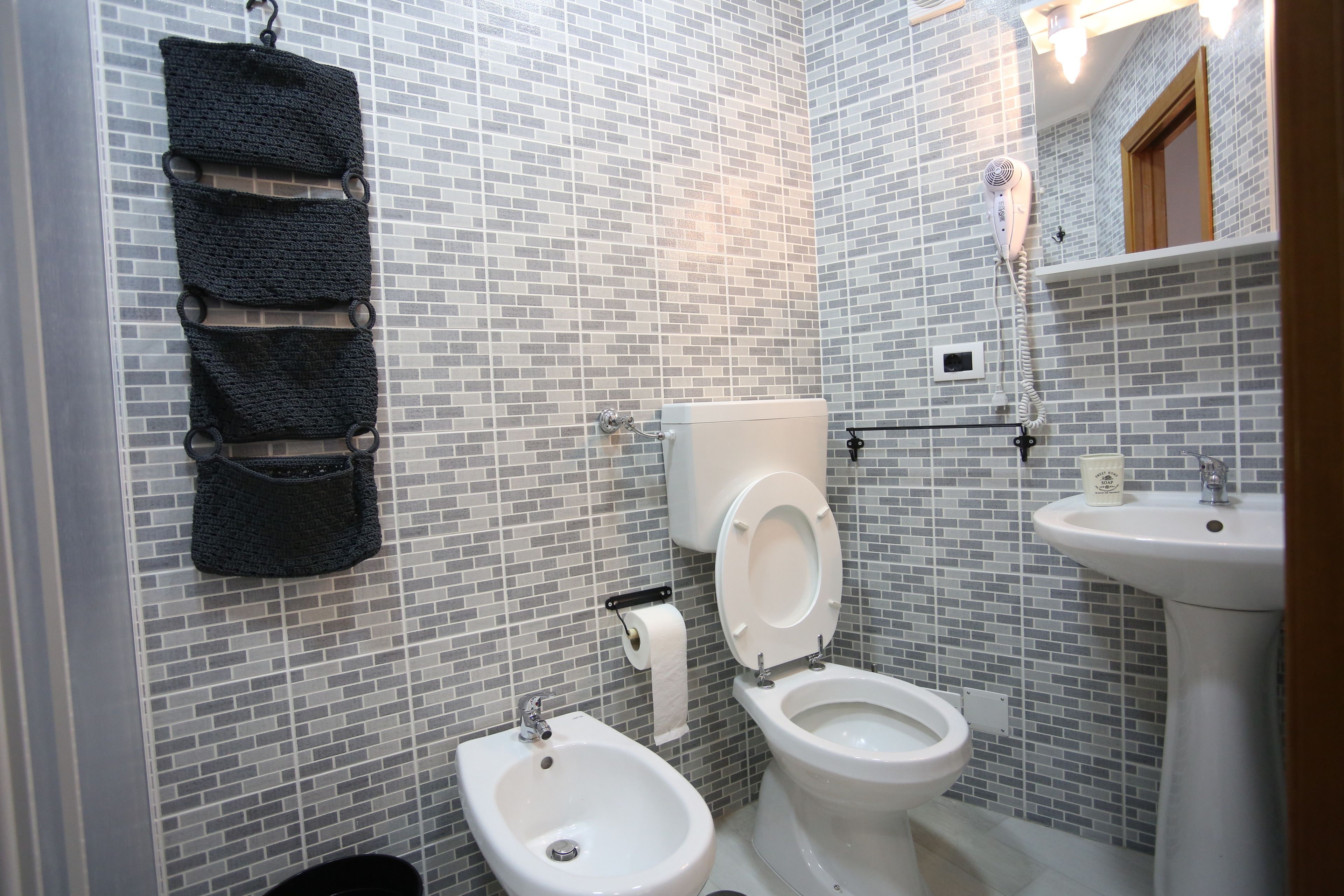A bathroom with a toilet, bidet, sink, and towel rack.