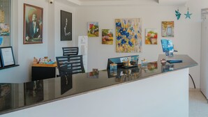 A reception desk with a glass top, surrounded by various artworks and a chair. - Hotel No37 (Kas)