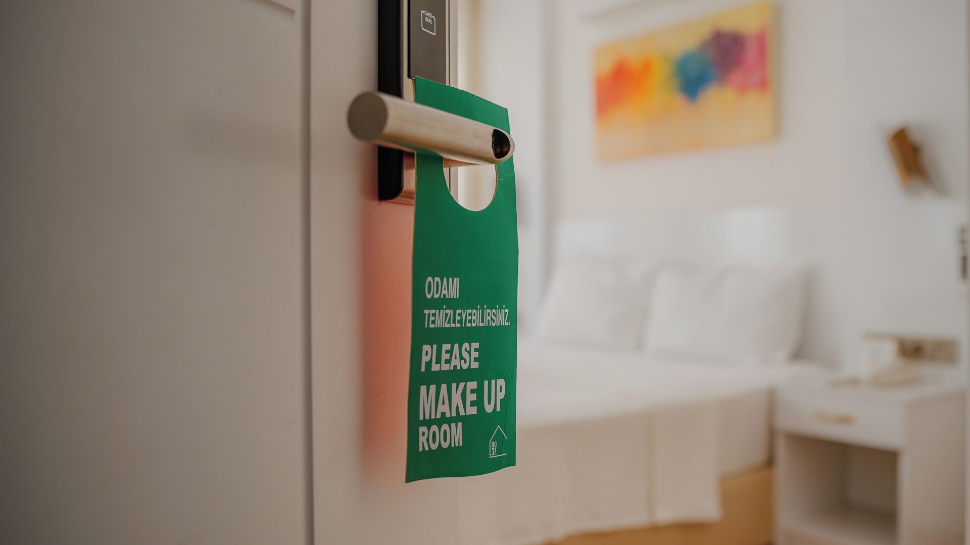 A green sign on a door requesting guests to make up the room.
