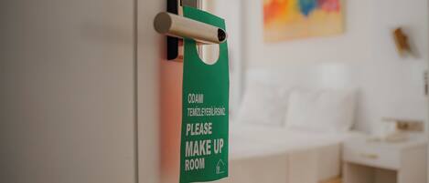 A green sign on a door requesting guests to make up the room.
