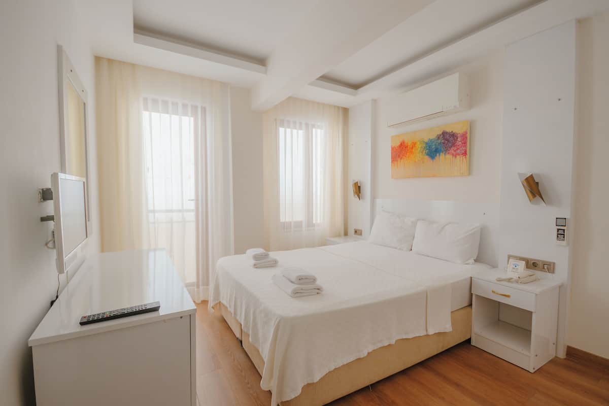 A hotel room with a bed, bedside table, and a TV on a stand.