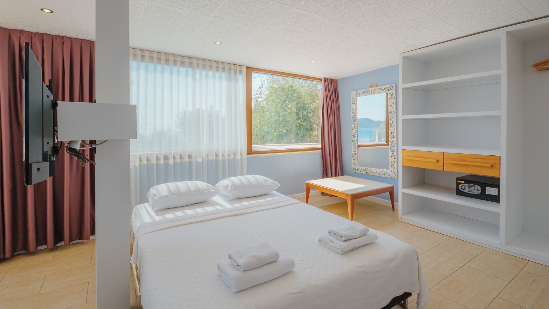 A hotel room with a bed, a desk, a TV, and a wardrobe.