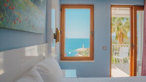 A bedroom with a bed, a window with a view of the sea, and a balcony with a chair. - Hotel No37 (Kas)