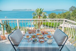 Een balkon met een ontbijttafel, met uitzicht op zee.