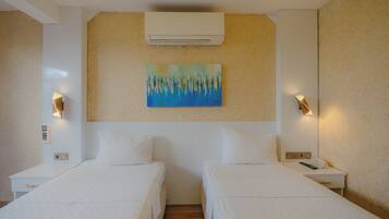Habitación de hotel con dos camas, un cuadro en la pared y dos mesitas de noche con lámparas.