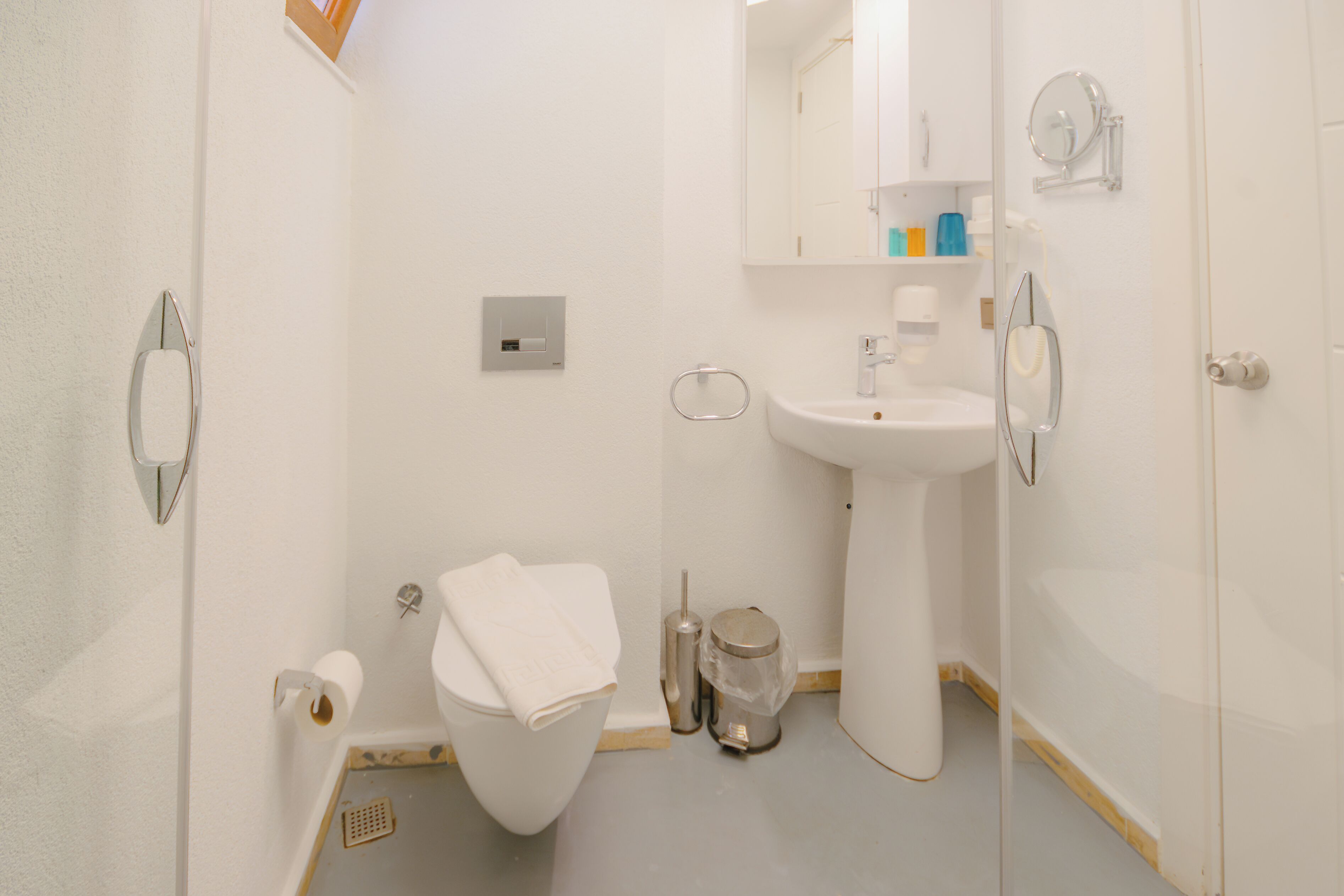 Un baño pequeño y moderno con inodoro, lavamanos y espejo.