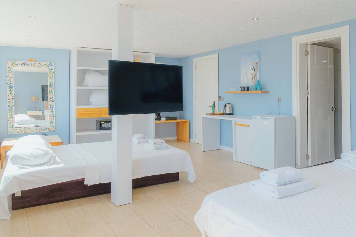 A hotel room with two beds, a TV, a desk, and a bathroom.