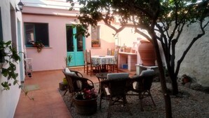 A patio area with wicker furniture, a table, and potted plants. - Sardinia International House (Zeddiani)