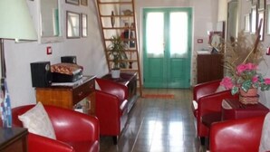 A room with red leather sofas, a wooden ladder, a green door, and a patterned floor. - Sardinia International House (Zeddiani)