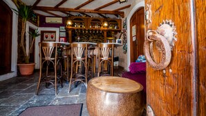 A rustic interior with wooden furniture, a bar area with shelves of bottles, and a stone floor. - El Asturiano (Tarifa)