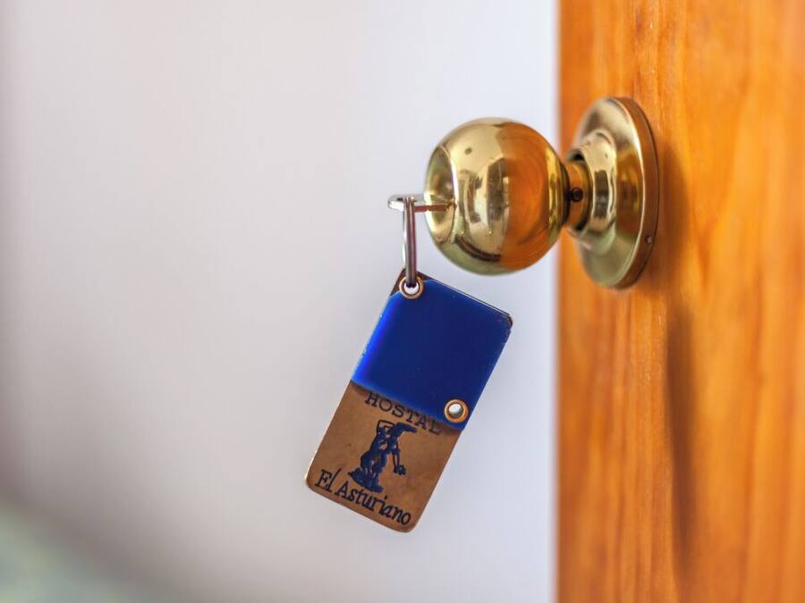 Una puerta con picaporte de latón y un llavero con una etiqueta que dice "HOSTAL El Asturiano".