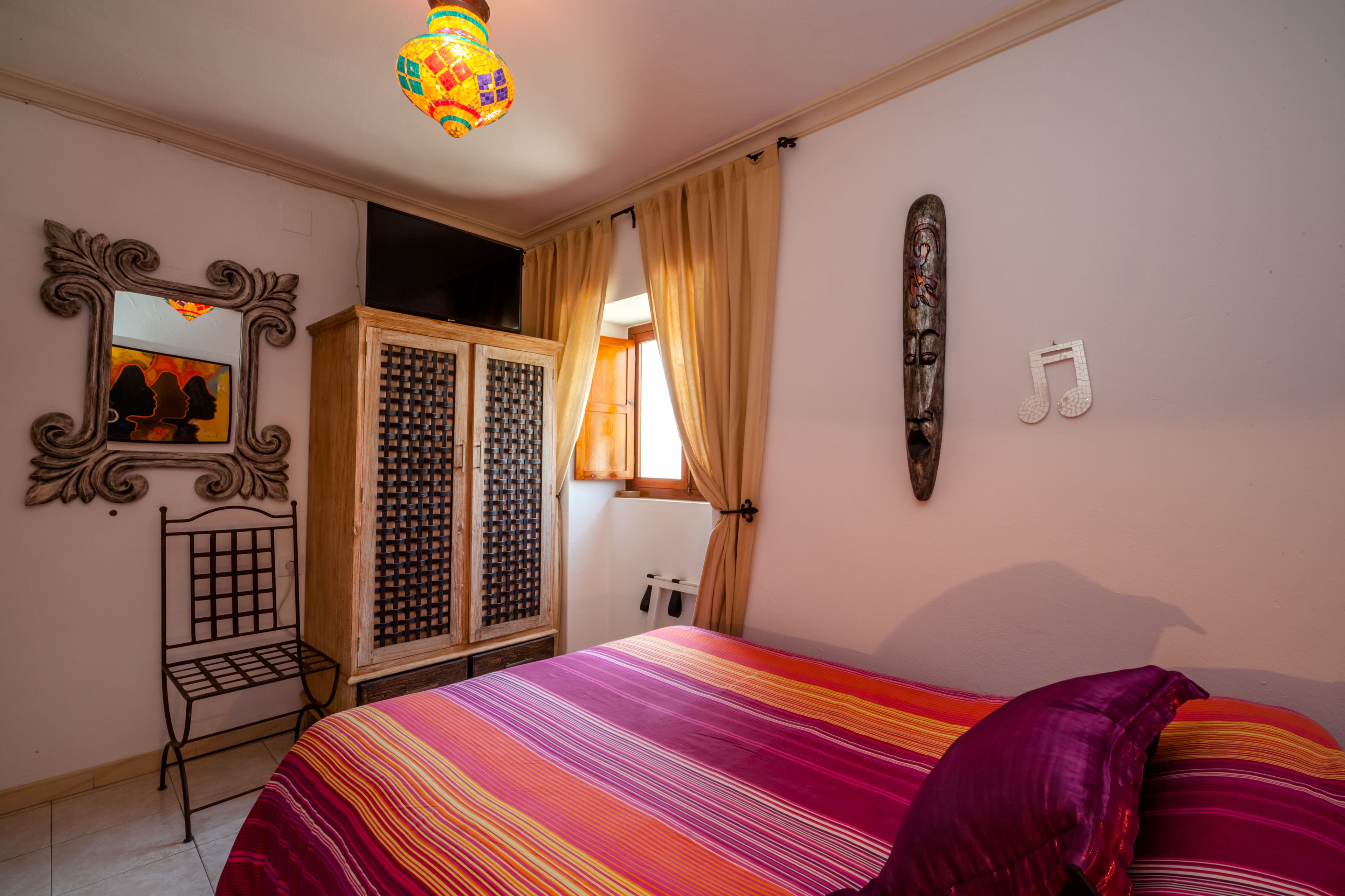 Un dormitorio con cama, armario, espejo y un adorno en la pared.