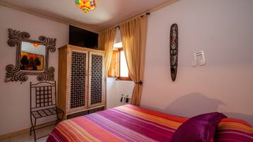 Un dormitorio con cama, armario, espejo y un adorno en la pared.