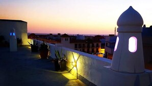 A rooftop terrace with potted plants and a white wall with a dome-shaped structure. - El Asturiano (Tarifa)