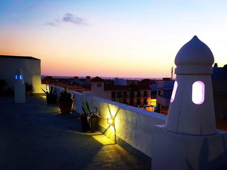 Una terraza en la azotea con plantas en macetas y una pared blanca con una estructura en forma de cúpula.