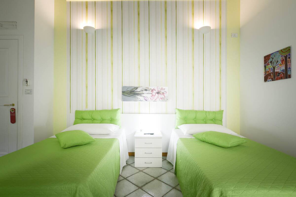 Ein Zimmer mit zwei Betten, einem Nachttisch und einer Wandleuchte.
