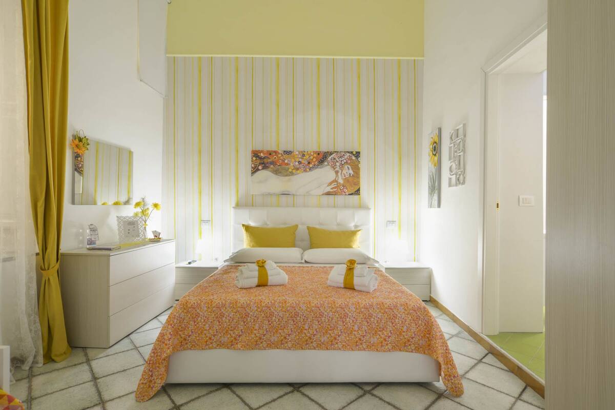 Ein Schlafzimmer mit Bett, Schminktisch, Spiegel und einem Bild an der Wand.