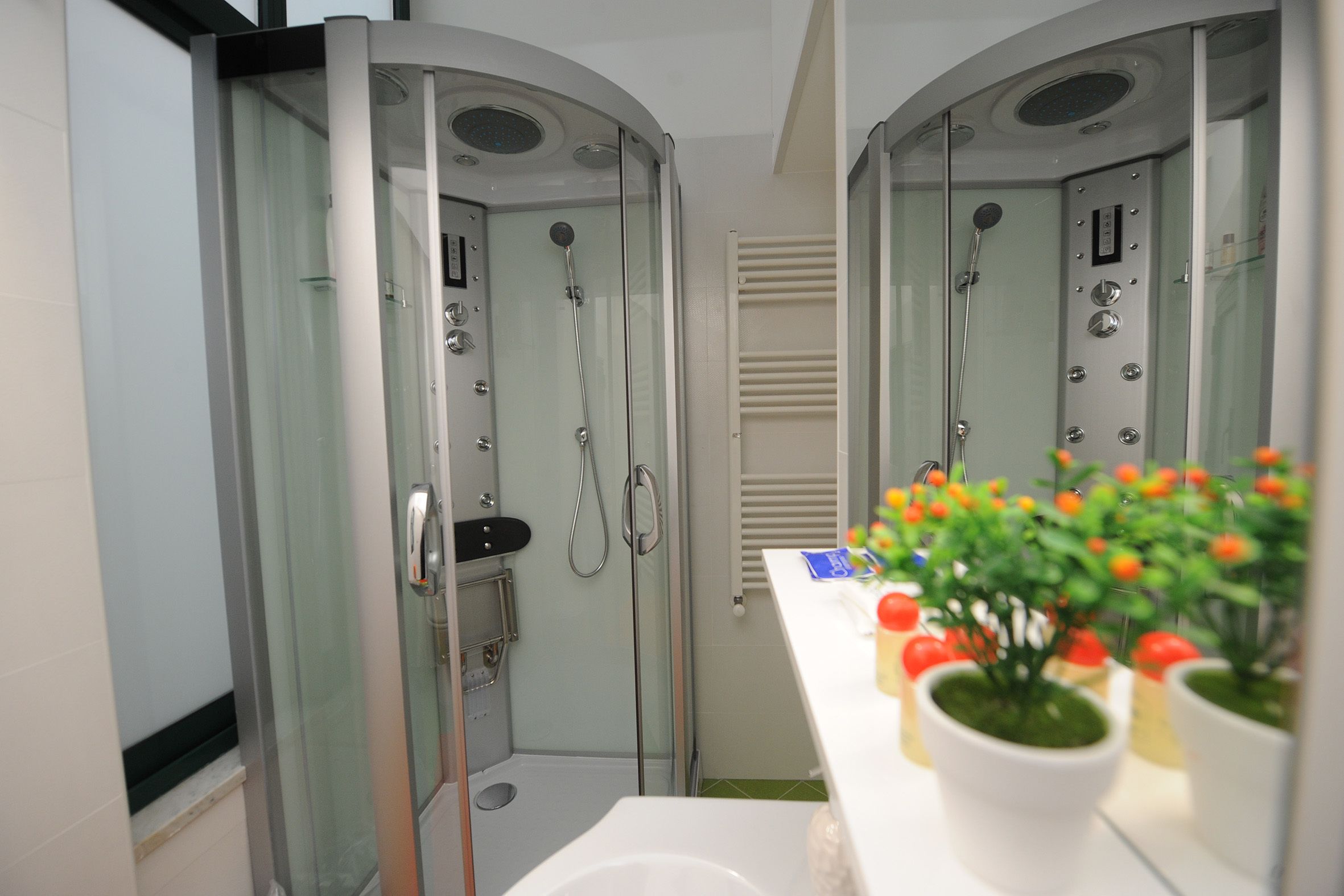 Un baño moderno con ducha de vidrio, un lavabo blanco y un espejo.