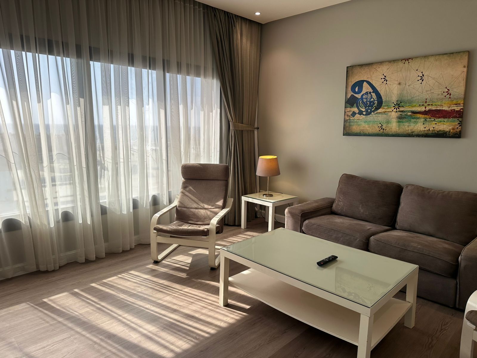 Een moderne woonkamer met een bank, fauteuil en glazen salontafel.