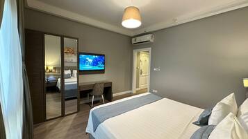 Une chambre d’hôtel avec un grand lit, un bureau avec une chaise, un téléviseur fixé au mur et un appareil de climatisation.