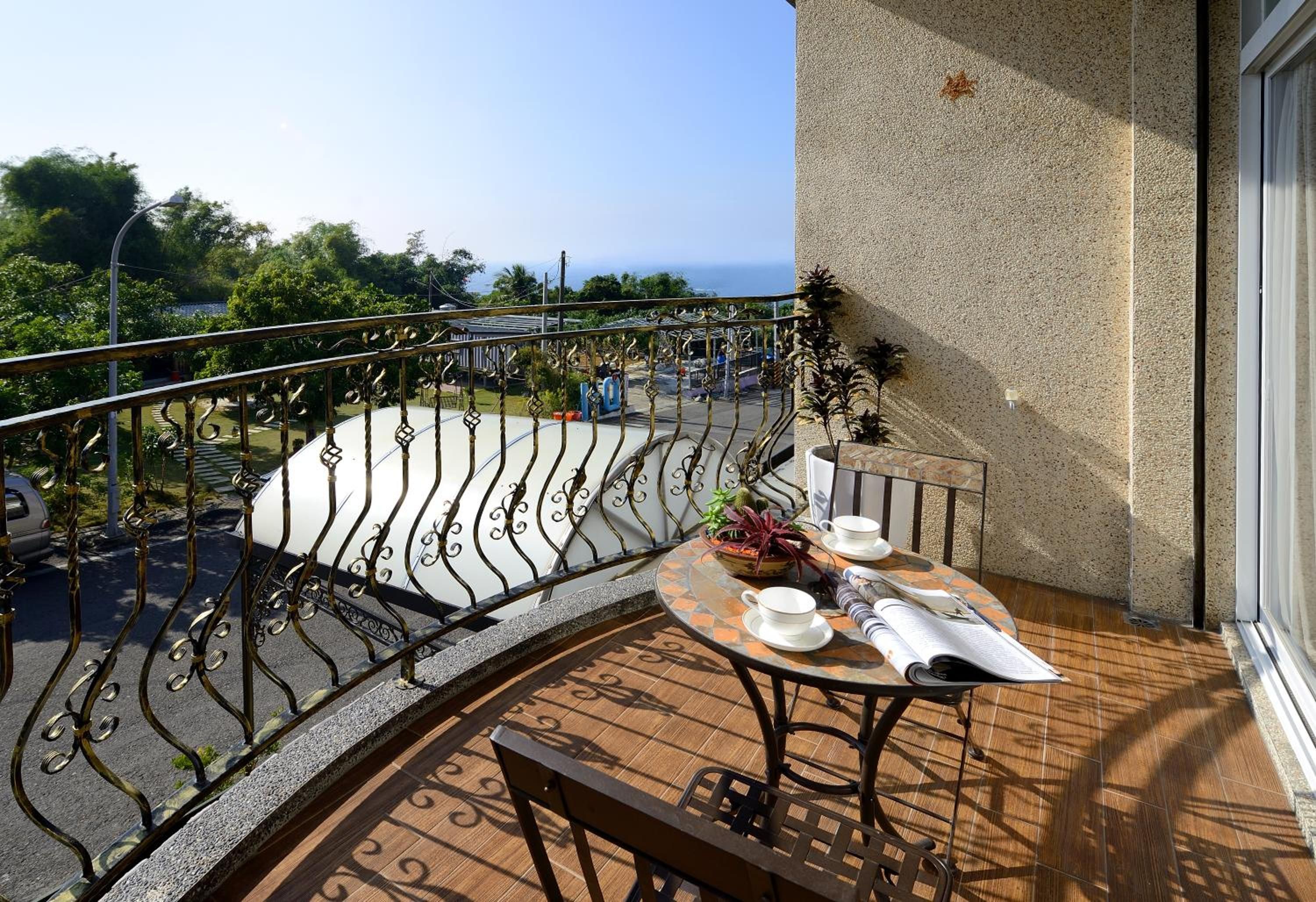 A balcony with a table set for two, a chair, and a potted plant.