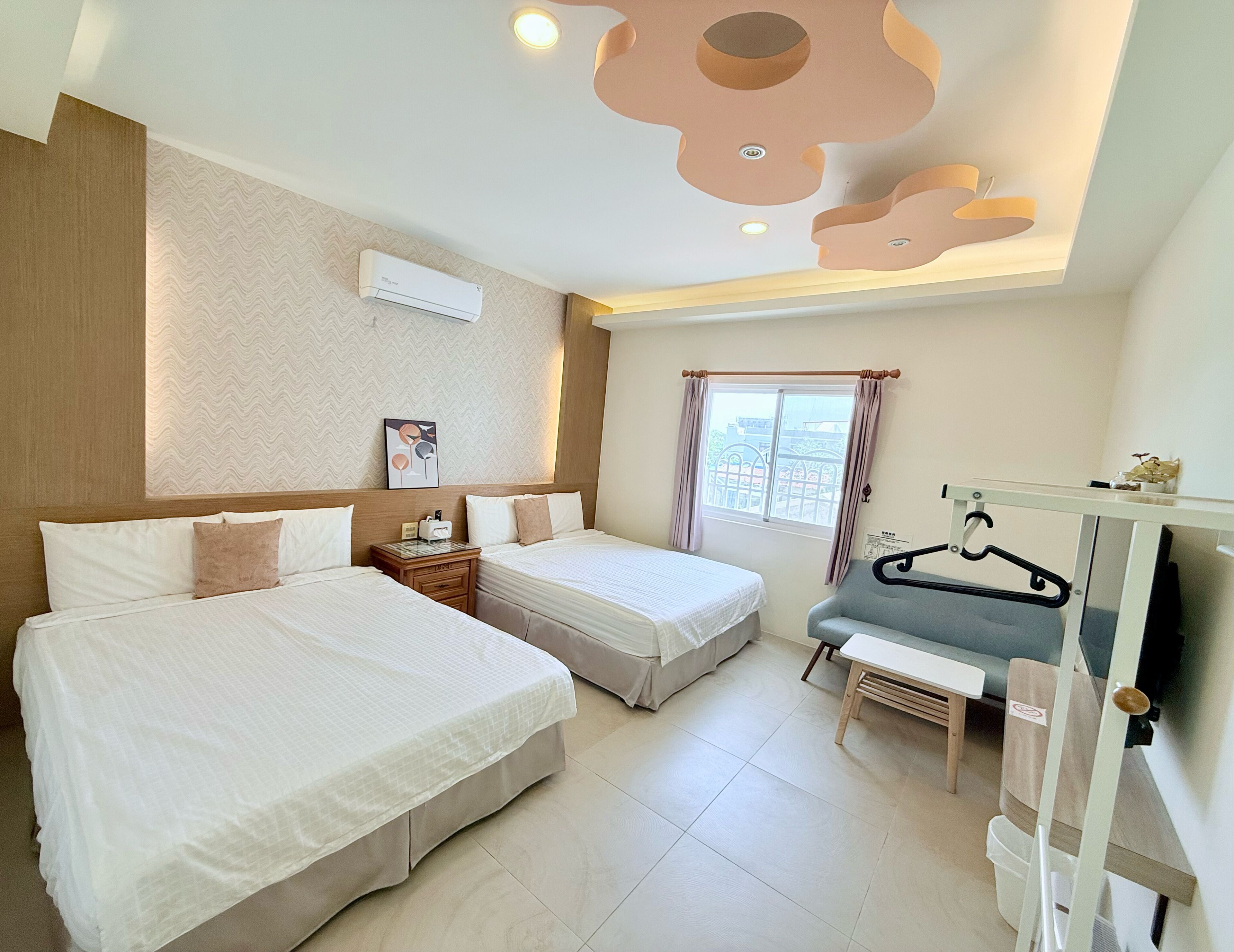 A hotel room with two beds, a desk, a chair, a TV, and a window with curtains.