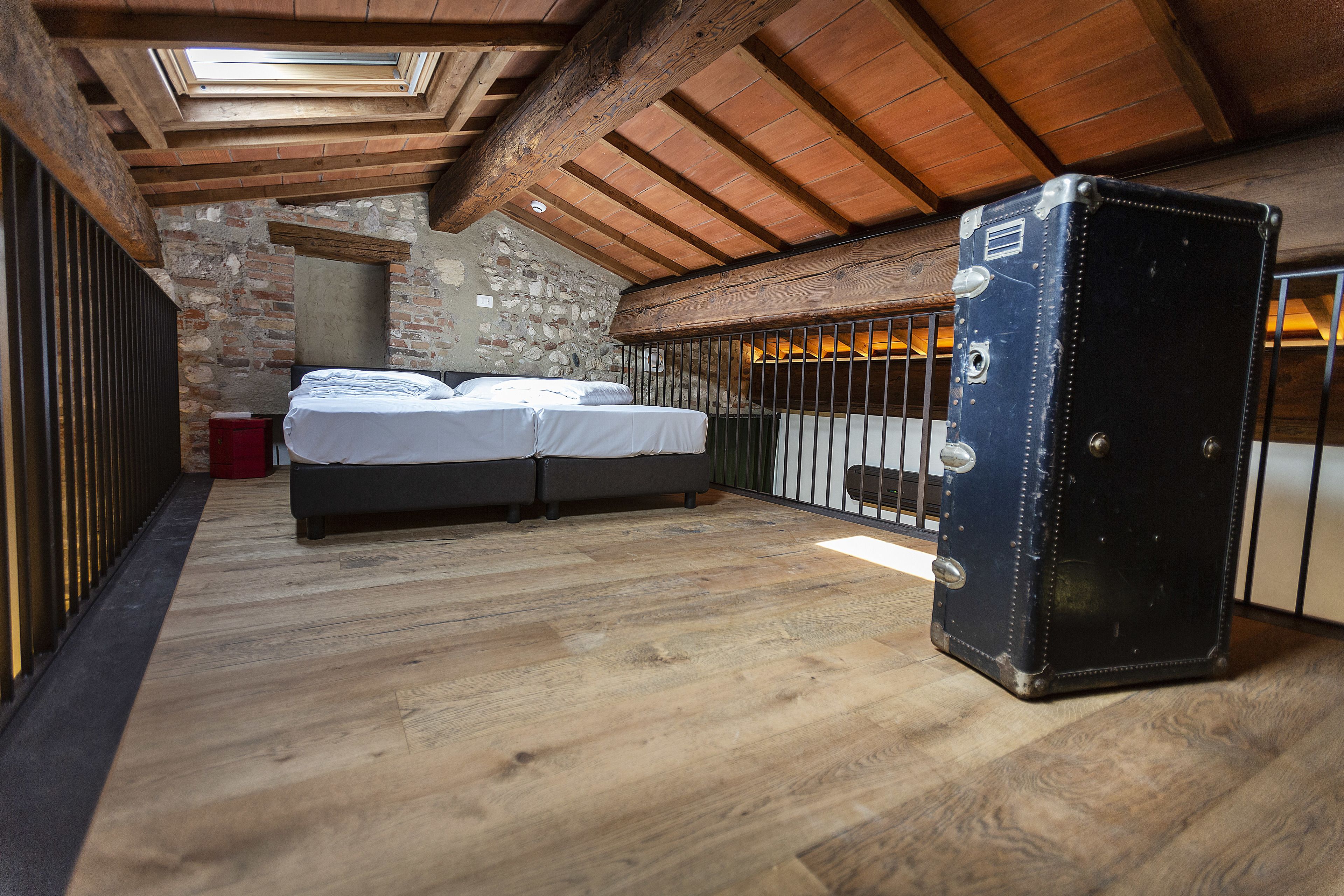A bedroom with a bed, a suitcase, and a stone wall.