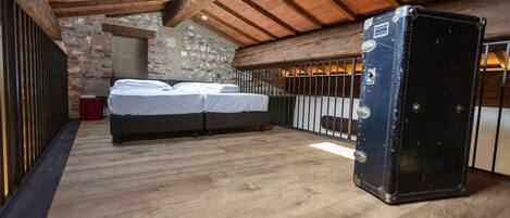 A bedroom with a bed, a suitcase, and a stone wall.