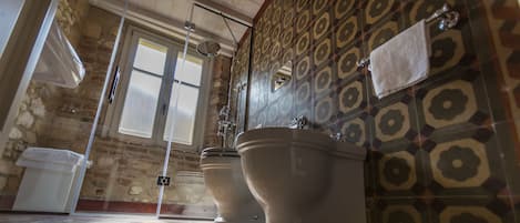 Un baño con dos inodoros, ducha y lavamanos.