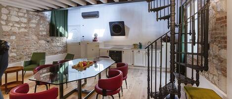 Una cocina moderna con una mesa de comedor de vidrio, sillas rojas y una escalera de madera.