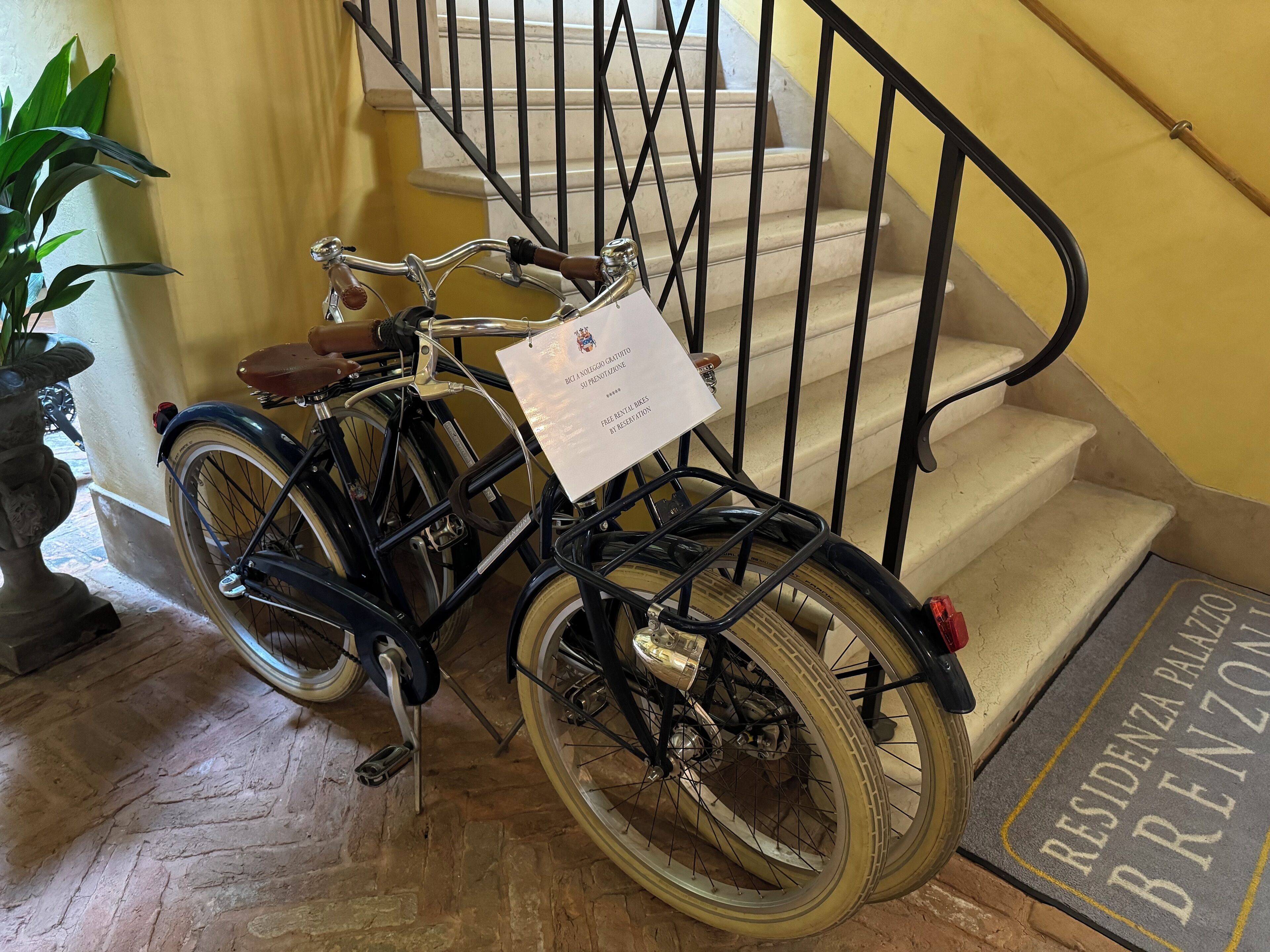 Una bicicleta estacionada junto a una escalera con un felpudo que dice "RESIDENZA PALAZZO BREZNZO".