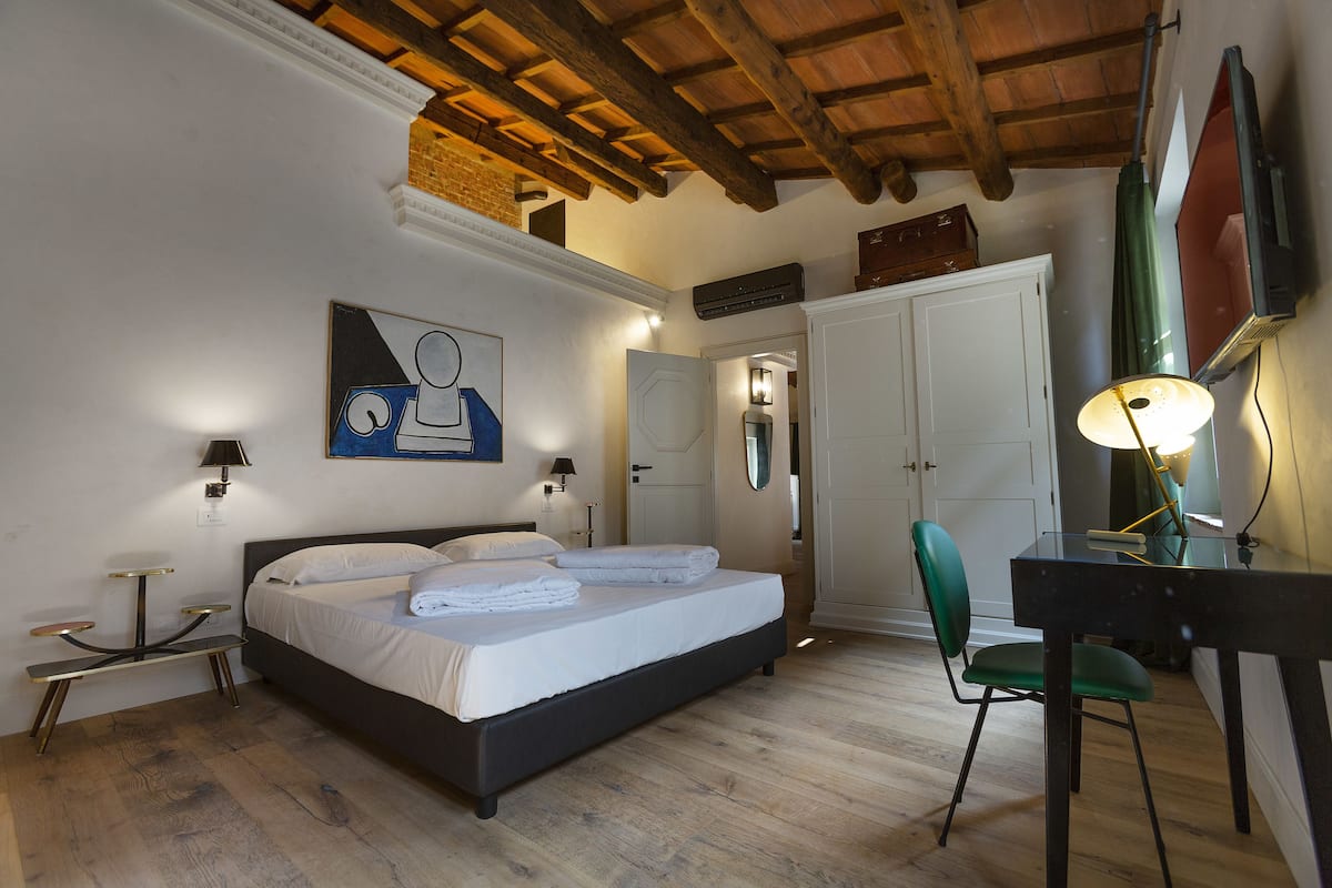 A bedroom with a bed, bedside tables, a desk, and a chair.