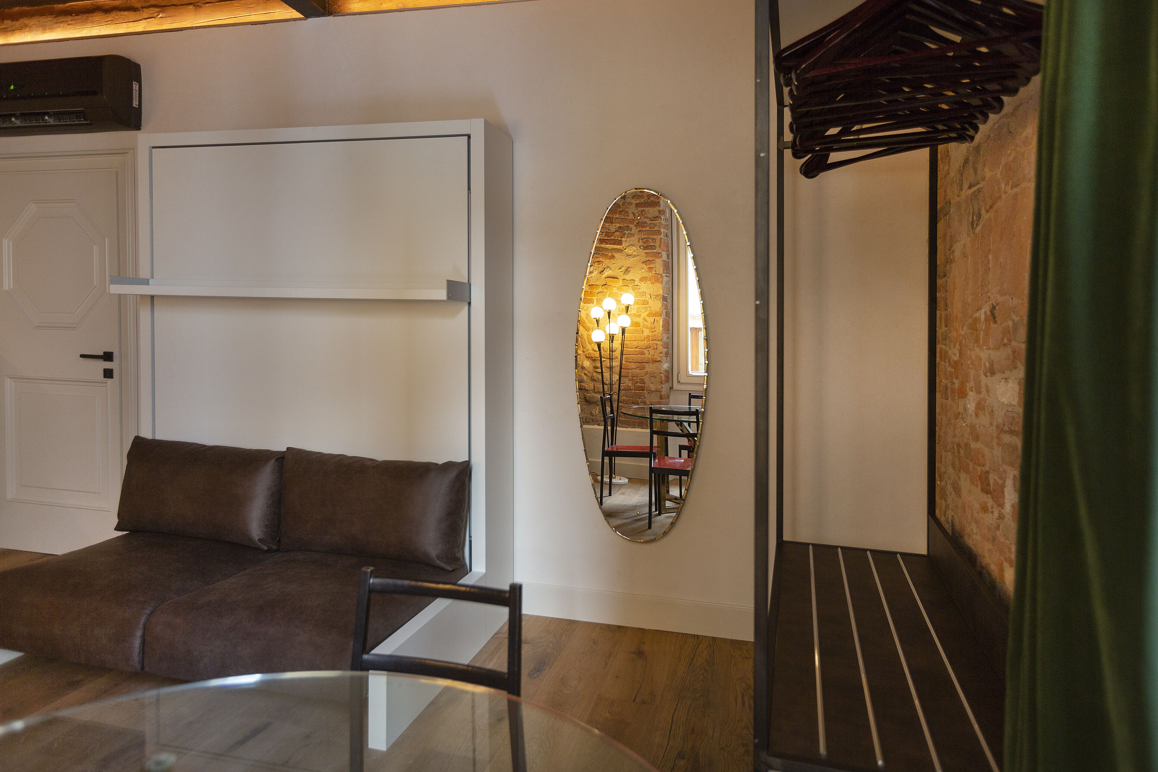 A room with a sofa, a round table, and a mirror on the wall.