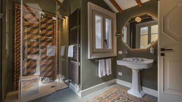Une salle de bain avec une douche à parois de verre, un lavabo blanc et des carreaux à motifs.