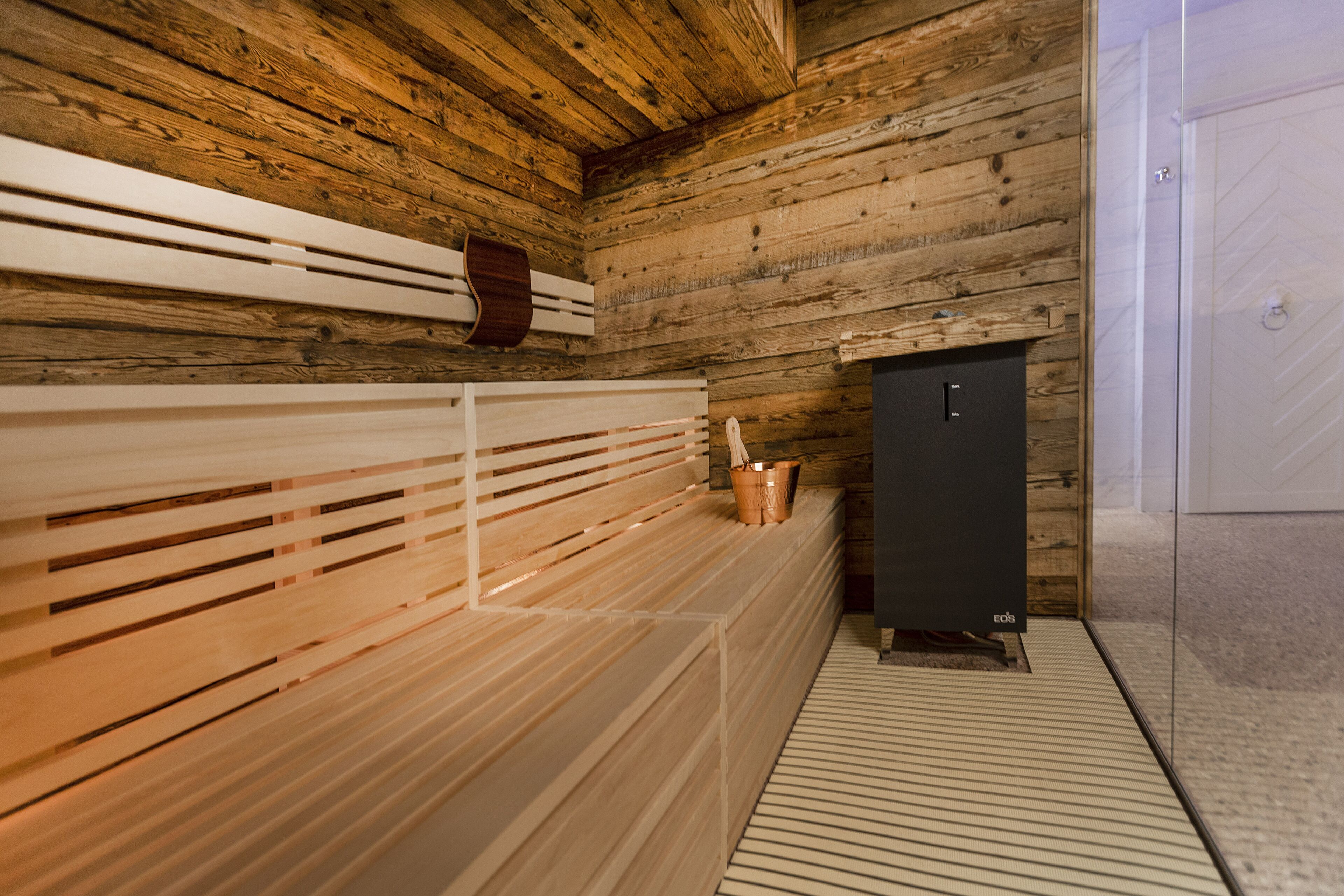 A sauna with wooden benches and a black cabinet.