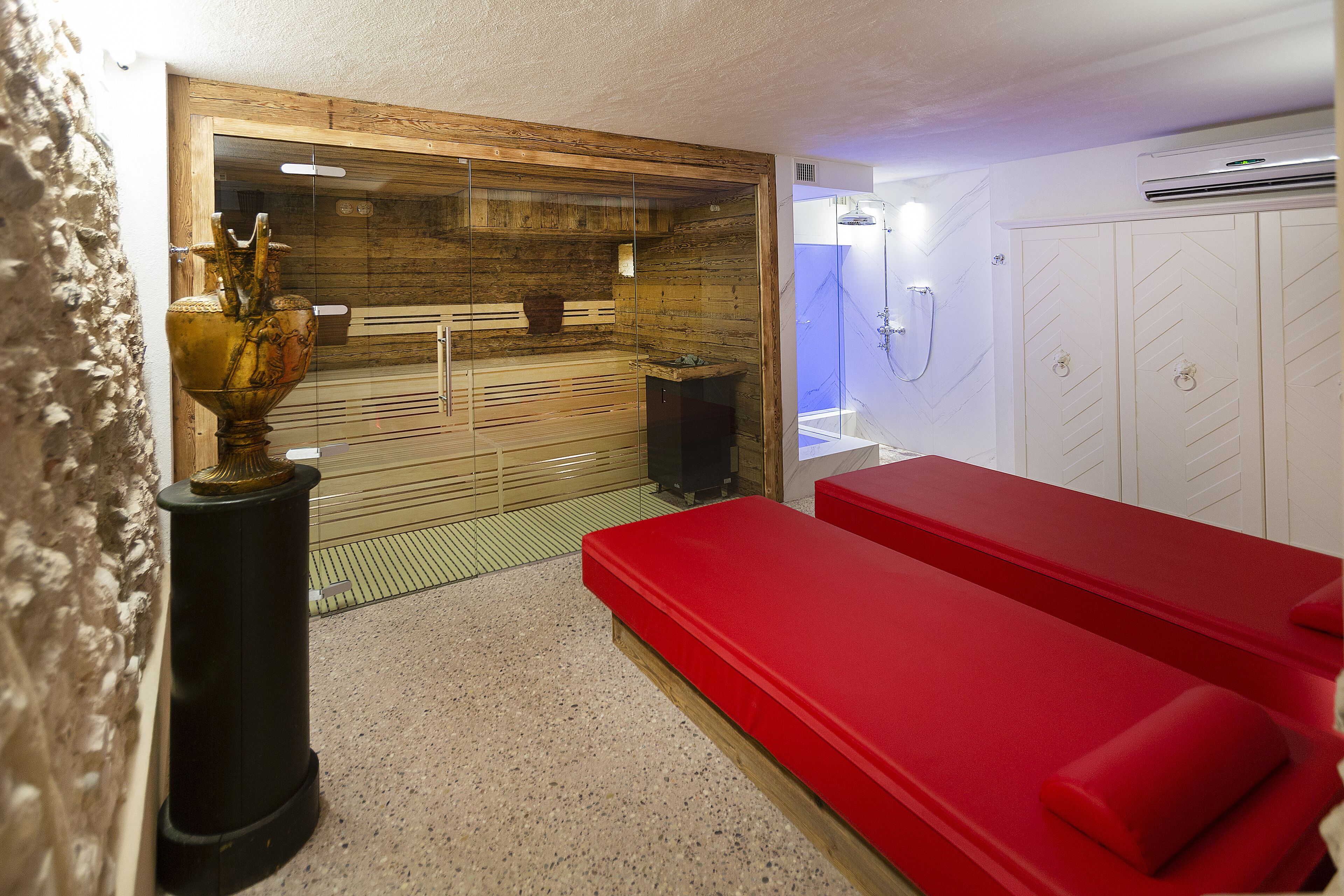 A sauna room with wooden walls, a red bench, and a glass enclosure.