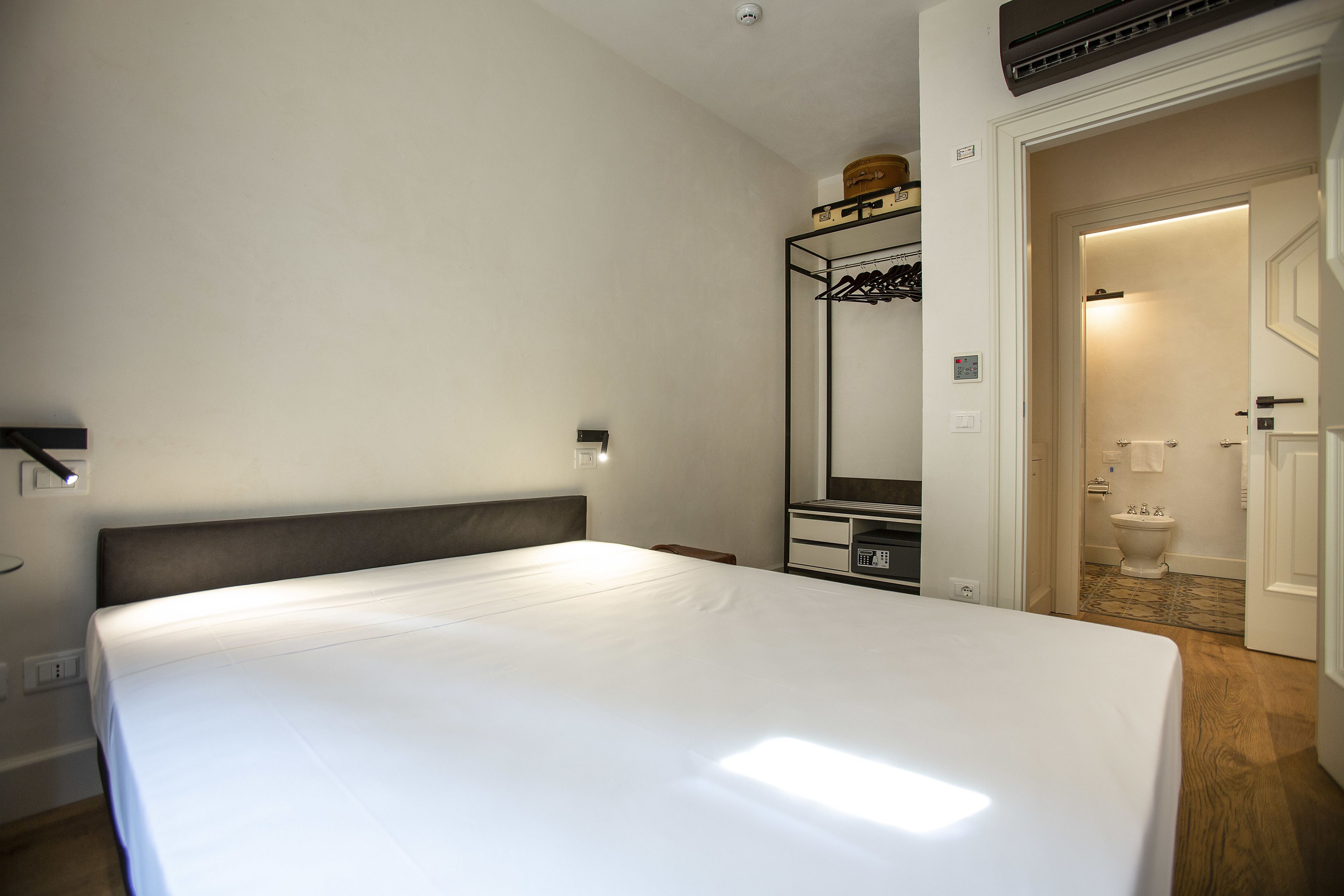 Hotelkamer met een groot bed, nachtkastje, spiegel en uitzicht op de badkamer.