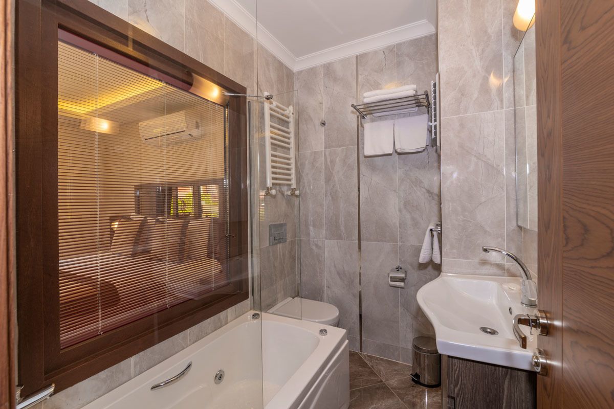 Un baño moderno con ducha de vidrio, bañera, lavamanos y retrete.