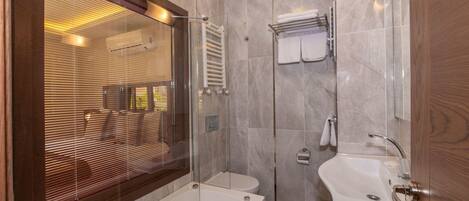 Un baño moderno con ducha de vidrio, bañera, lavamanos y retrete.